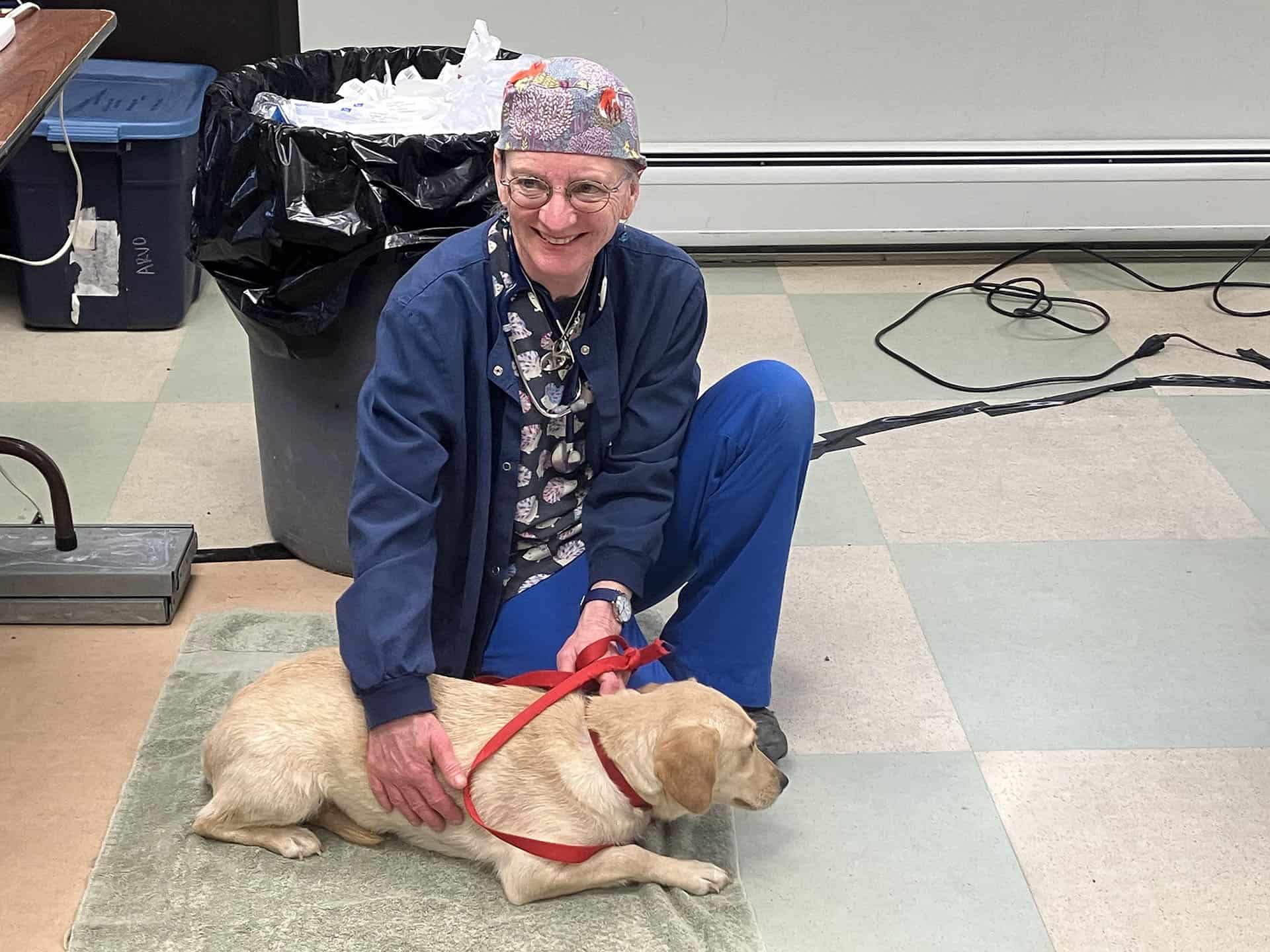 small yellow lab with smiling vet on the floor